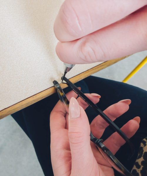 Étudiant de l'école d'optique de Lille réalisant l'ajustement minutieux d'une monture de lunettes à l'aide d'un tournevis.
