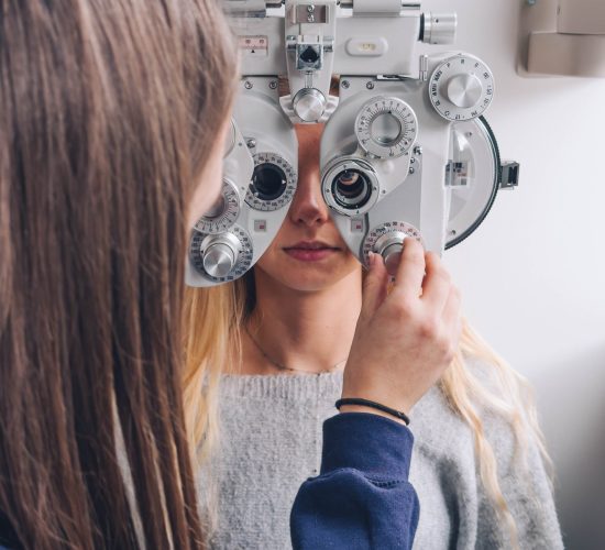 Étudiante en BTS opticien-lunetier en formation initiale réalisant un examen de vue avec une tête de réfraction.